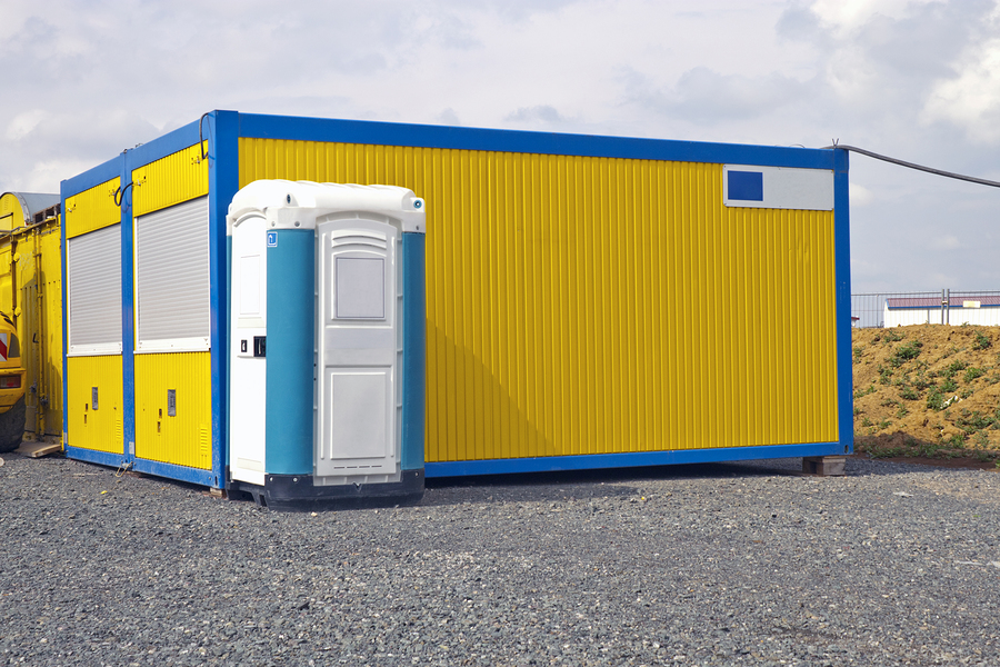 yellow industrial site container and a white porta toilet