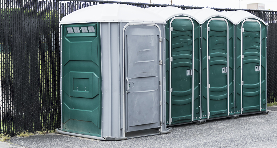 four green portable toilets